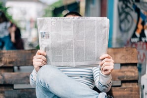man sitting on a bench reading a newspaper