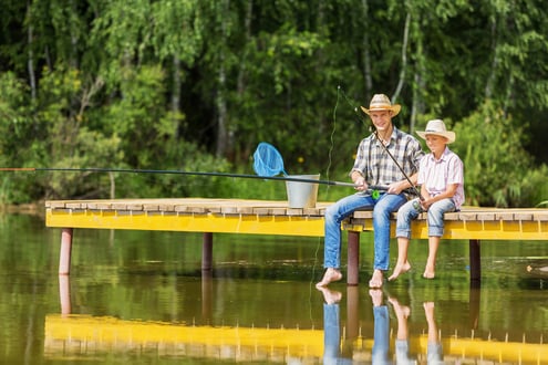 Father and son sitting on bridge and fishing