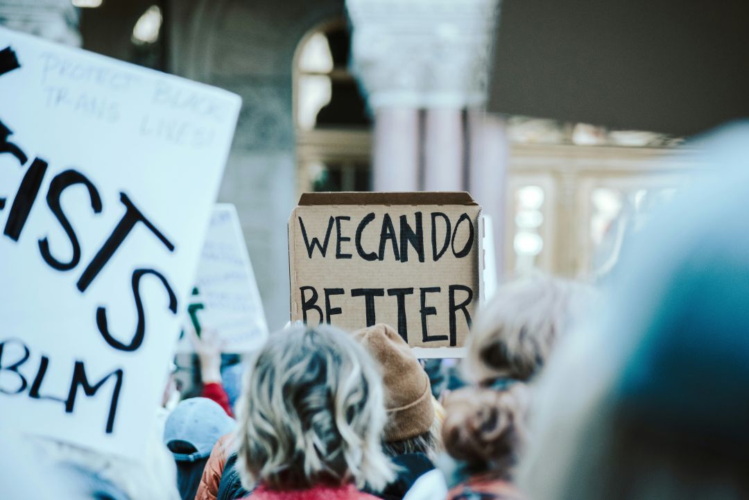 we can do better written on a cardboard sign