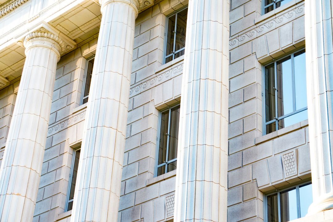 stone columns in front of a brick building with windows